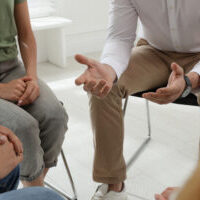 Psychotherapist working with group of drug addicted people at therapy session, closeup