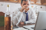 man at desk drinking liquor, why does someone use in the first place?